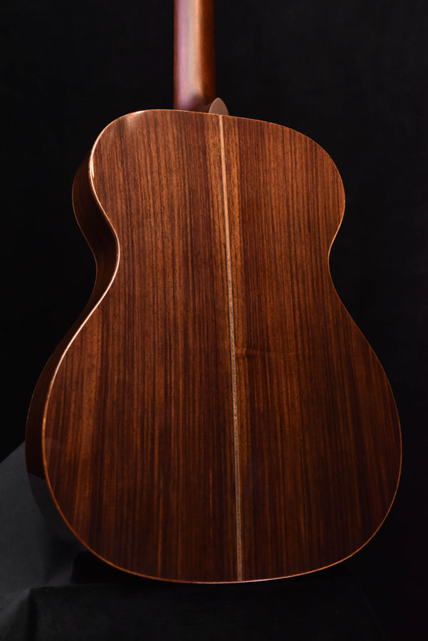 Back view of dark brown acoustic guitar with vertical wood grain pattern