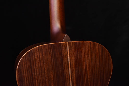 close-up of dark brown acoustic guitar back with curved body contour