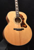 Front view of natural wood acoustic guitar with black pickguard and rosette