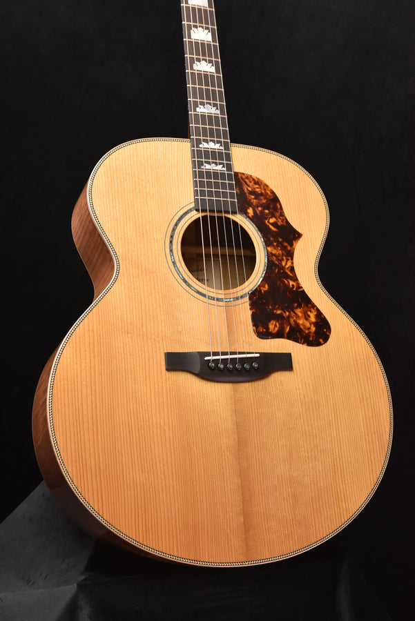 Front view of natural wood acoustic guitar with black pickguard and rosette