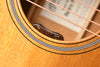 Acoustic-electric guitar bridge area with “vol” and “tone” controls under strings