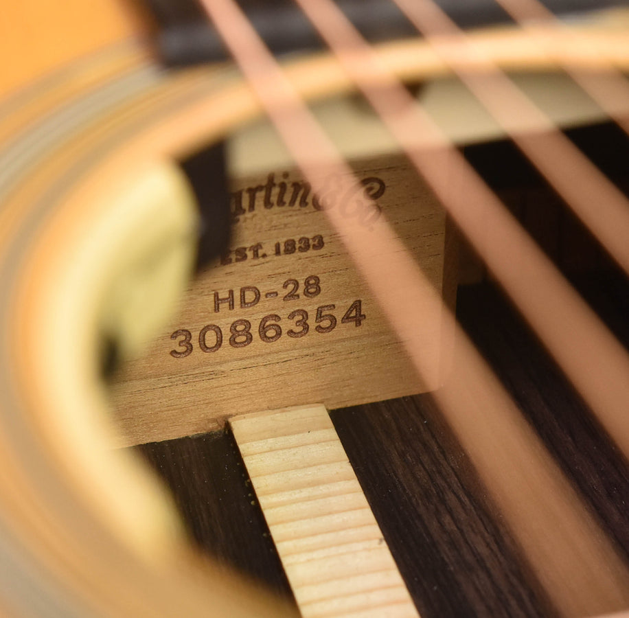 Acoustic guitar headstock with Martin logo and printed model numbers behind strings
