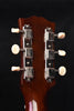 Acoustic guitar headstock with tuning machines on a dark brown wood panel