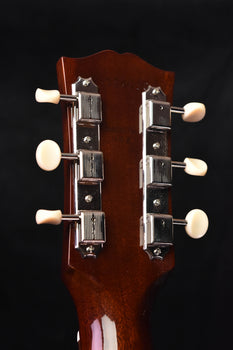 acoustic guitar headstock with tuning machines on a dark brown wood panel