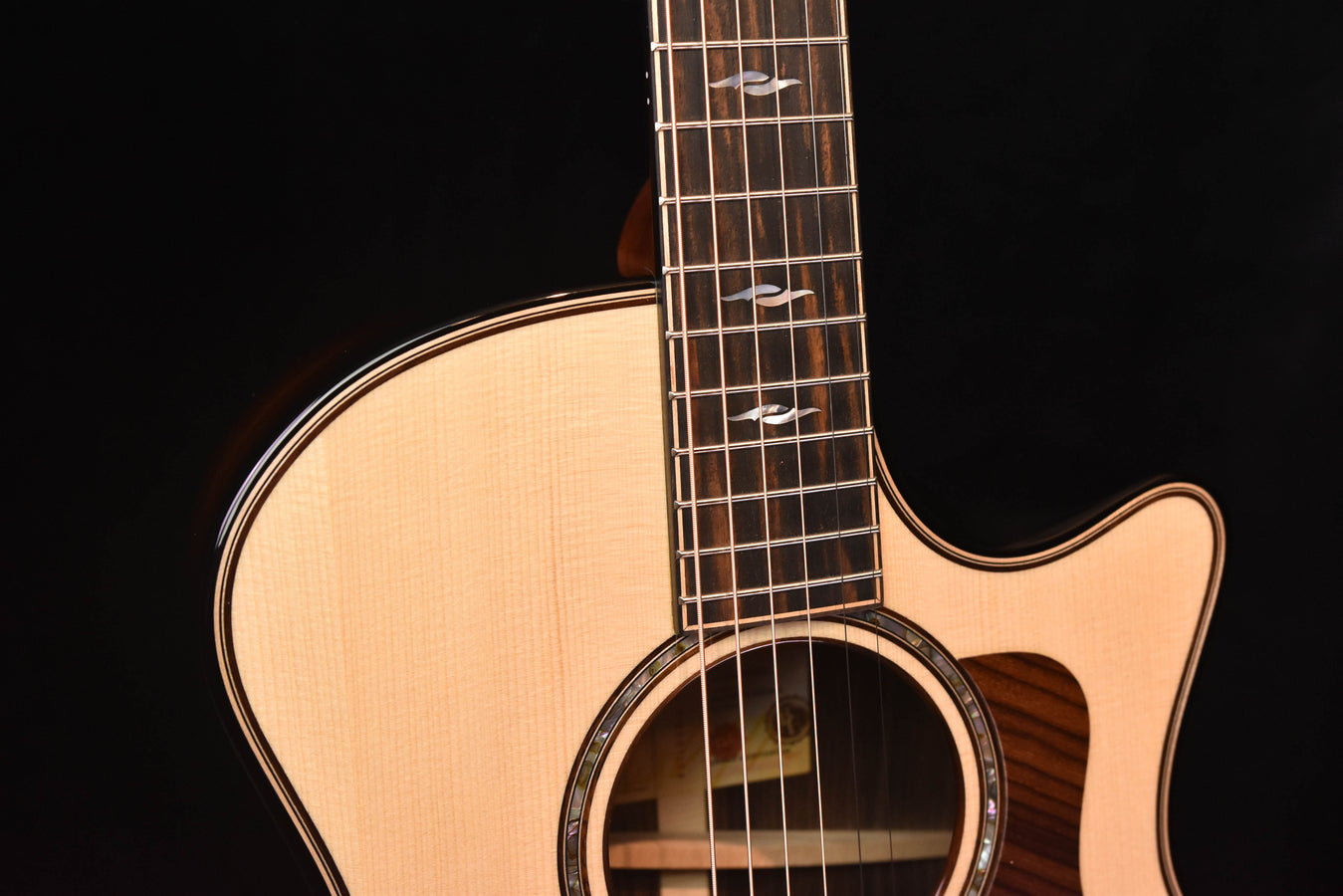 Acoustic guitar upper bout and neck joint with fretboard and strings.