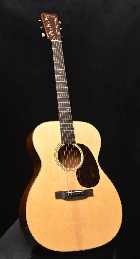 Martin acoustic guitar with light wood body, sound hole, and black bridge
