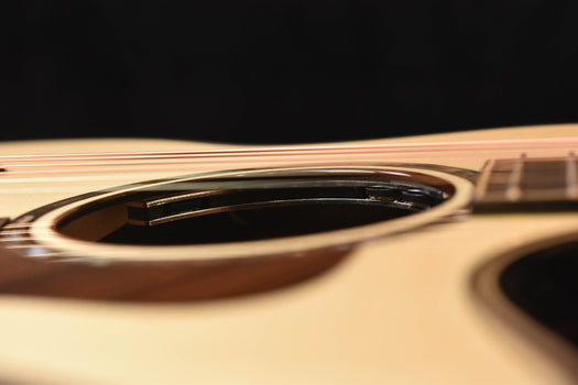 acoustic guitar soundhole area with dark rosette and strings near the neck.