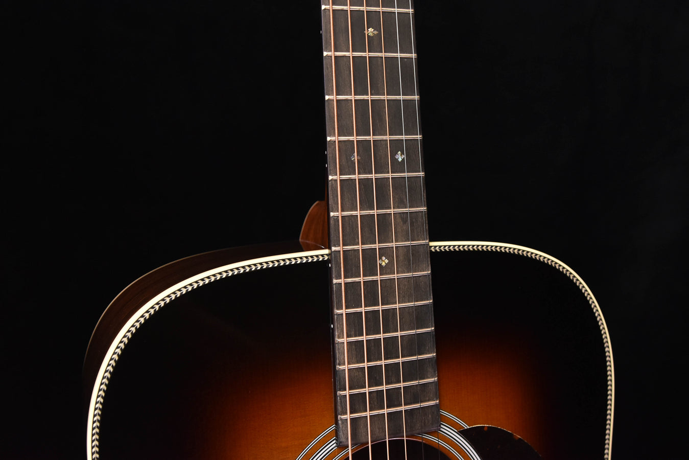 Acoustic guitar neck with dot fret inlays and white binding on upper bout