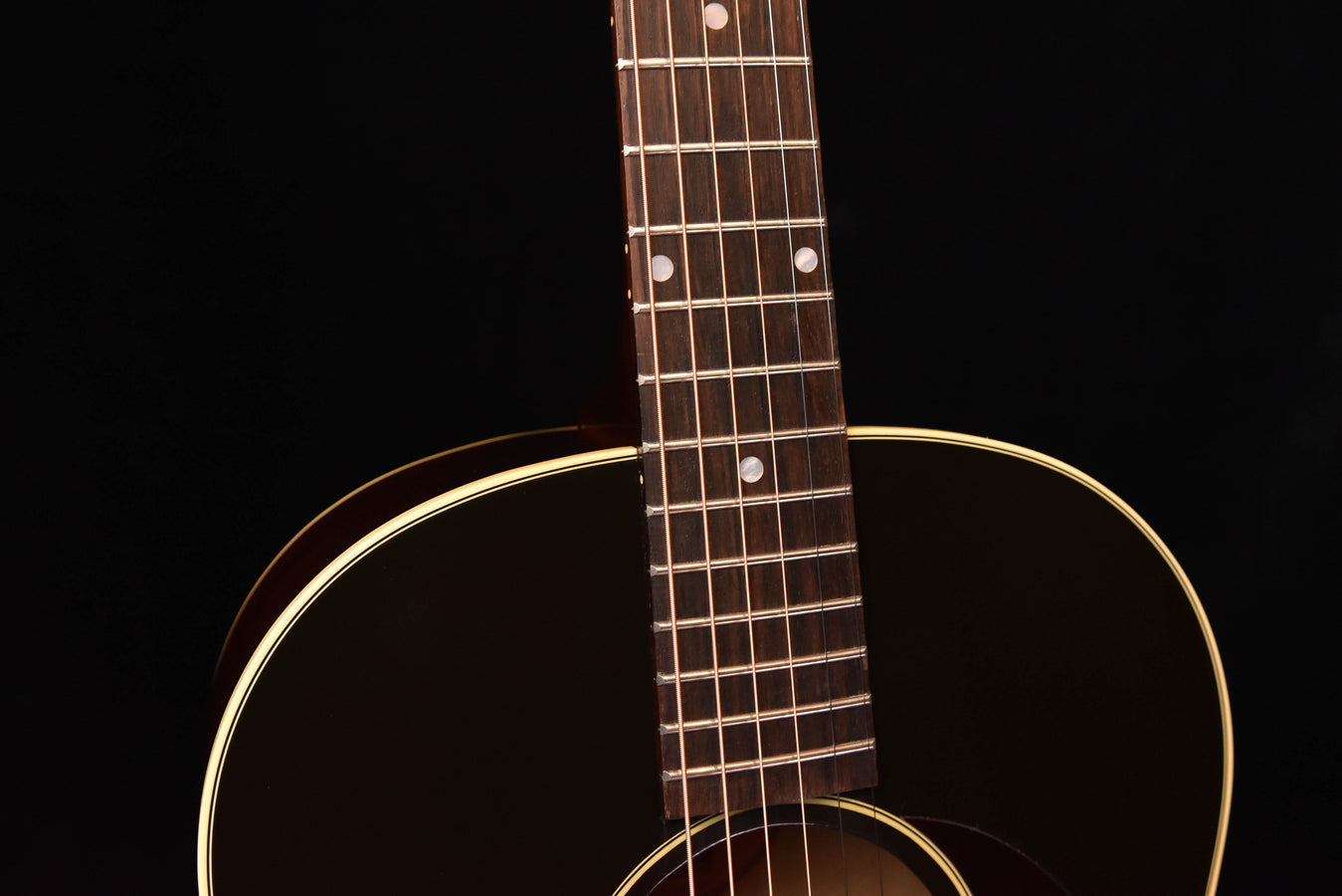 Acoustic guitar close-up of neck and fretboard with body sound hole and binding