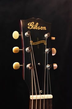 acoustic guitar headstock with gibson logo, chrome tuners, and nut with nut slots