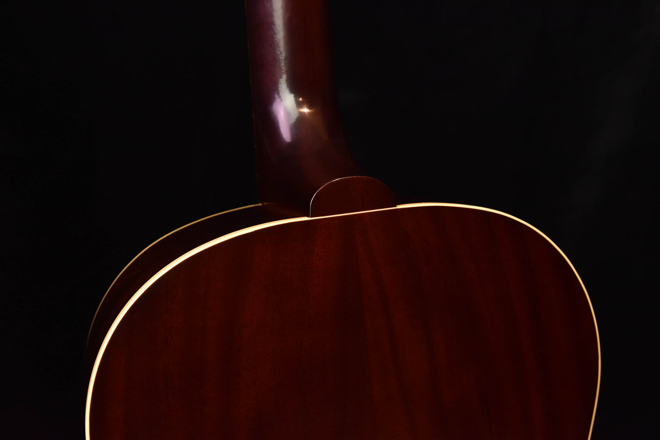 Acoustic guitar body close-up with glossy dark wood and cream outline binding
