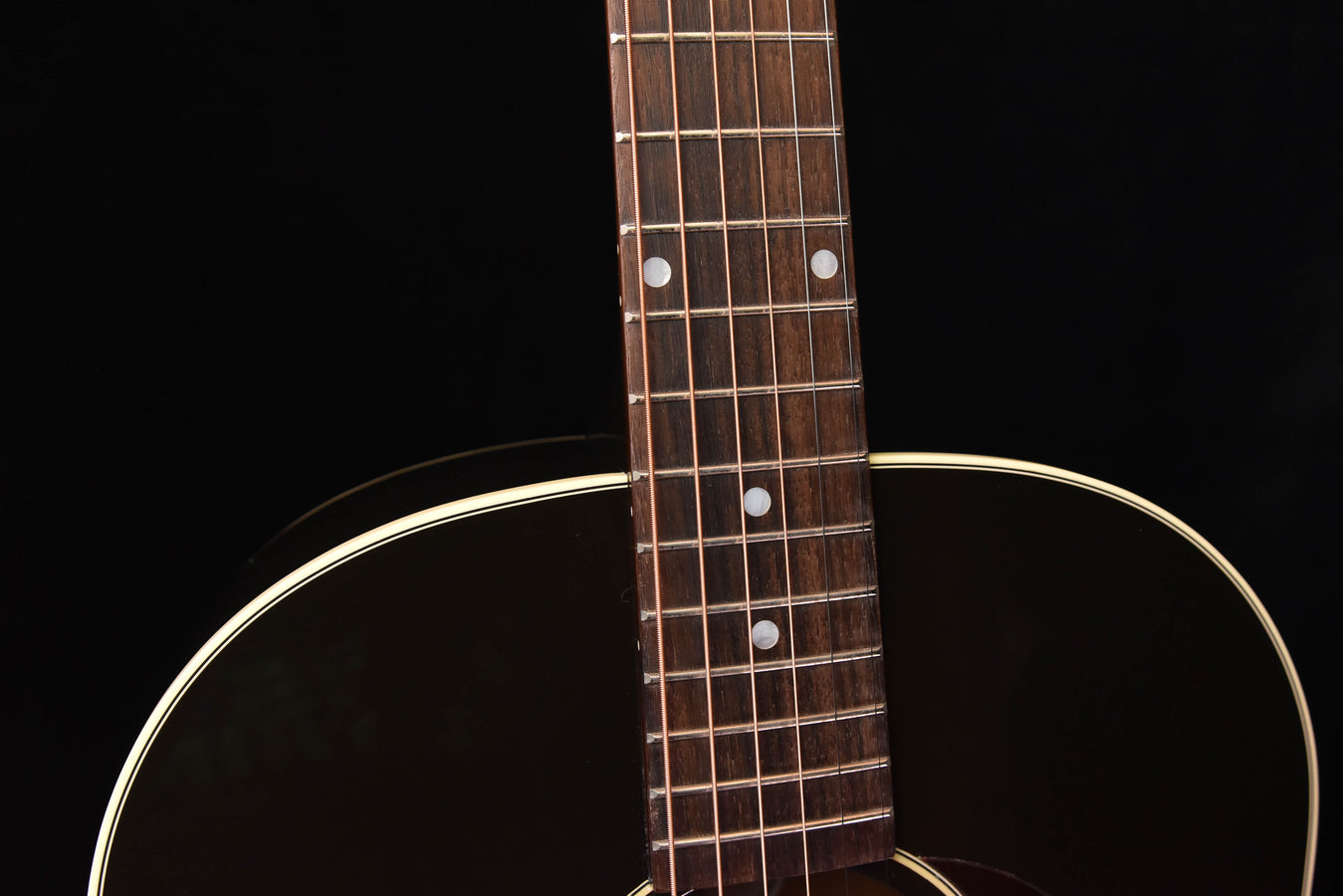 Acoustic guitar neck and headstock area with dot inlays and sound hole edge