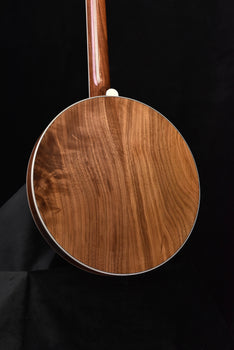 brown wooden banjo body with white binding and upright neck