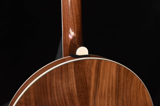 banjo headstock and neck above brown wooden rim with white binding