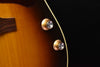 Acoustic-electric guitar with gold control knobs near the bridge