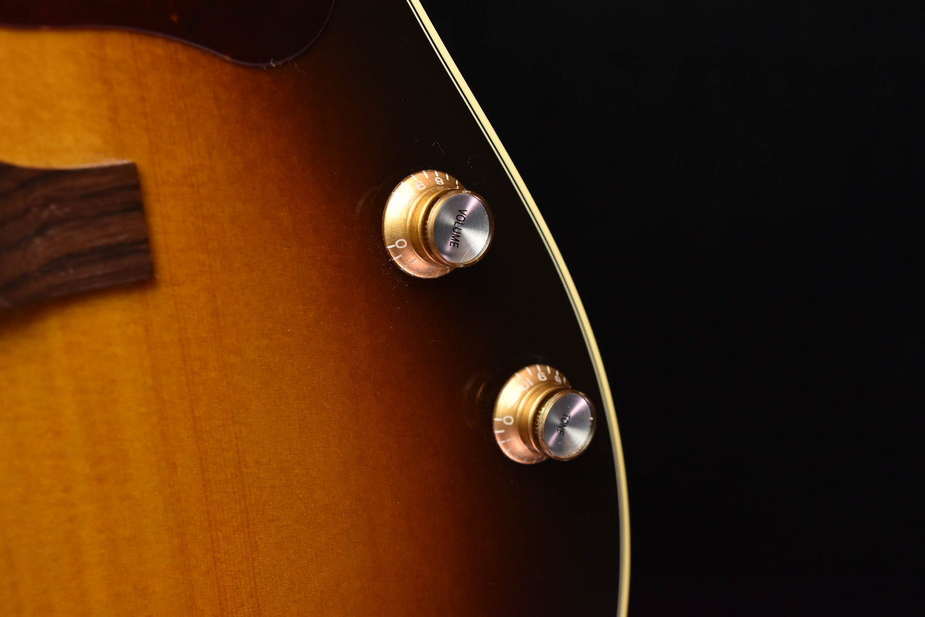Acoustic-electric guitar with gold control knobs near the bridge