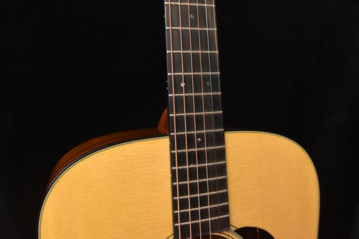 dreadnought acoustic guitar neck and upper bout close-up with frets and strings