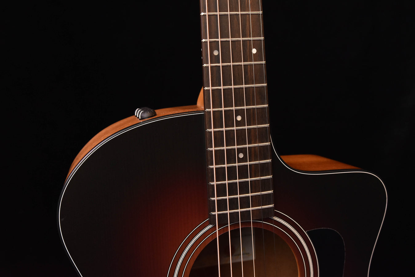 Acoustic guitar close-up on strings, fretboard, and upper body edge.