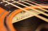 Serial marking on the headstock over orange-brown wood finish