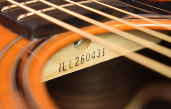 serial marking on the headstock over orange-brown wood finish