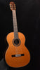 Classical guitar with natural wood finish and fretboard, standing upright.