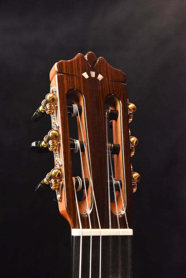 Classical guitar headstock with tuning pegs on both sides, warm wood tone.