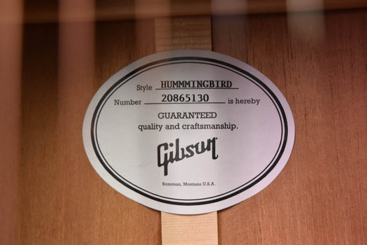 round hummingbird style label on the guitar body with guaranteed quality text