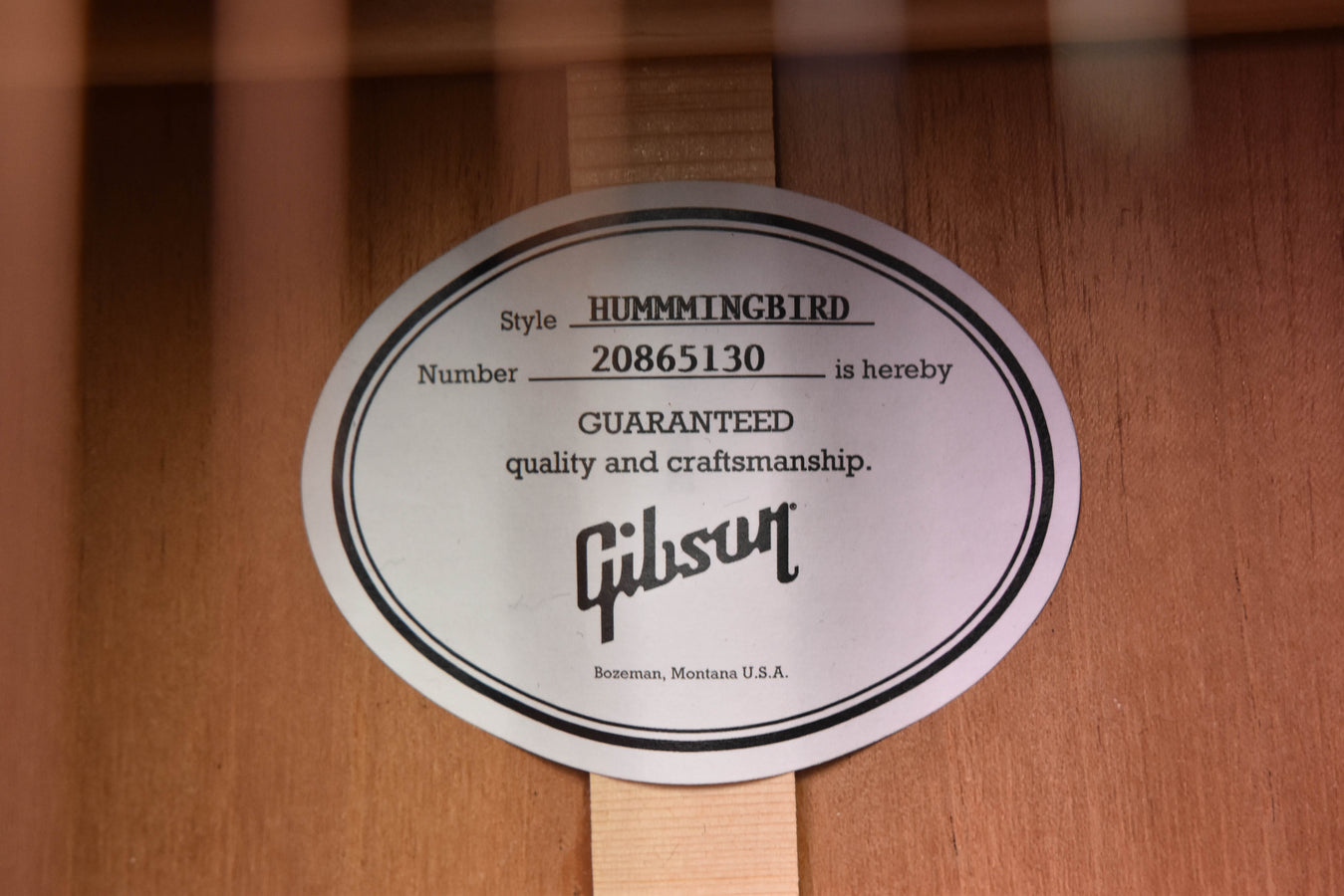 Round Hummingbird style label on the guitar body with guaranteed quality text