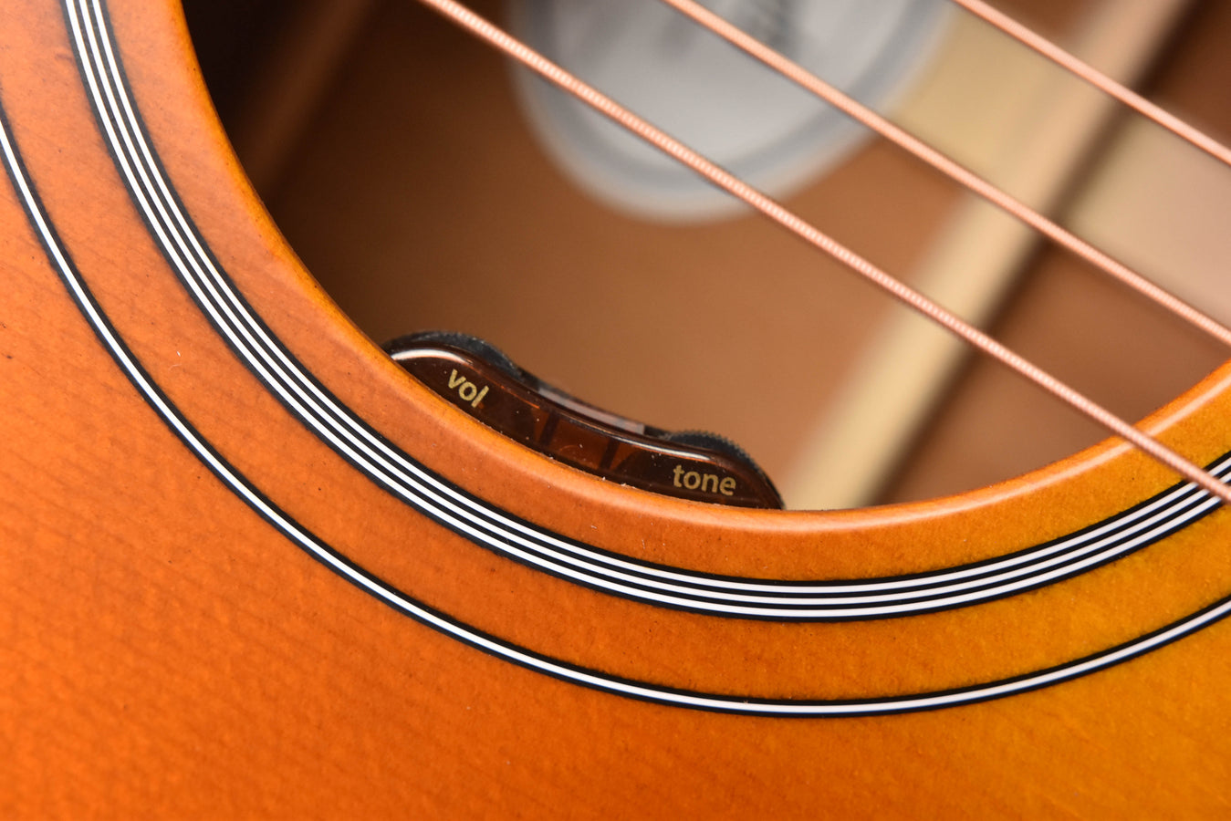 Acoustic guitar controls with black vol and tone knobs on an orange finish top