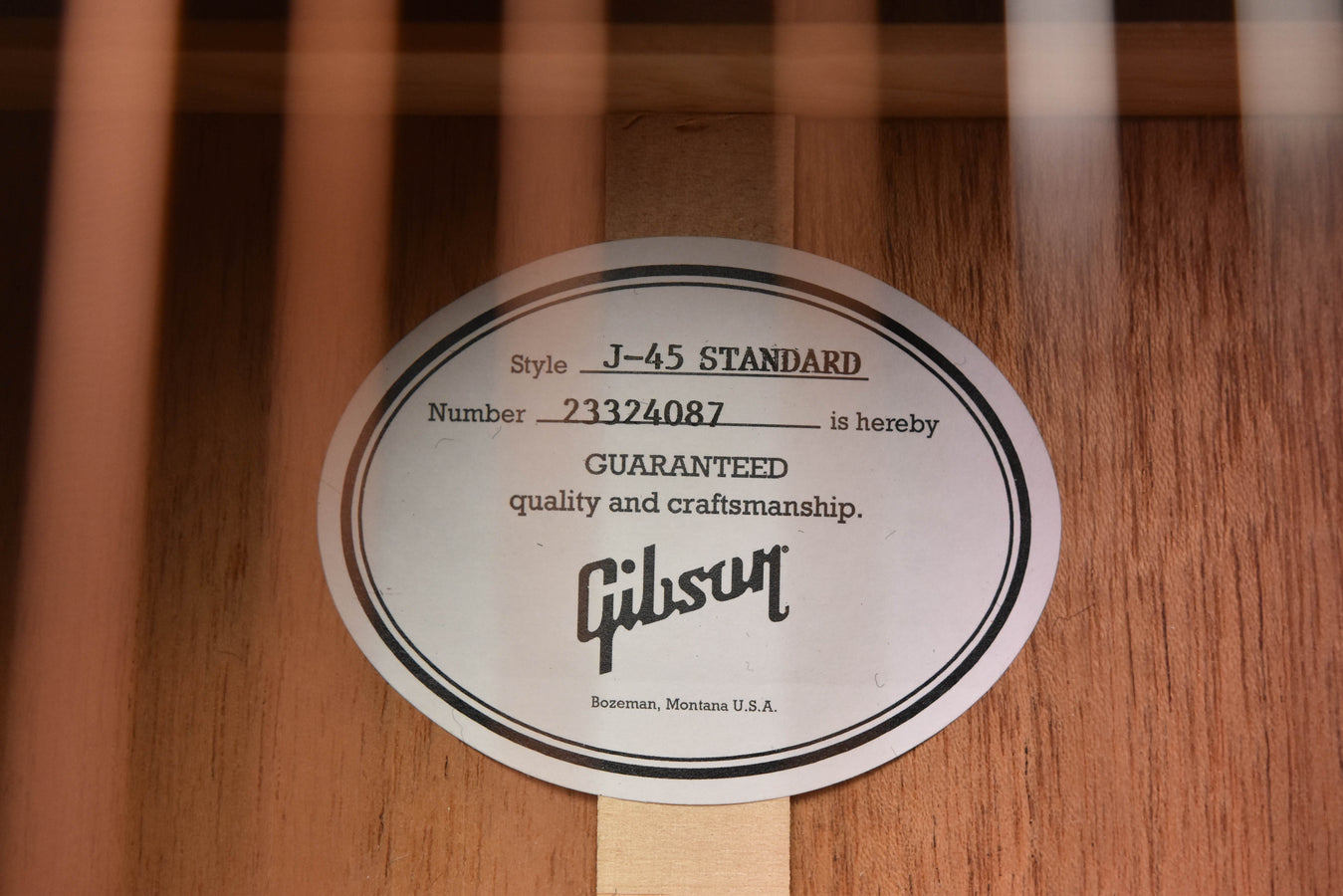 Guitar label plate with Gibson-style text on light wood body