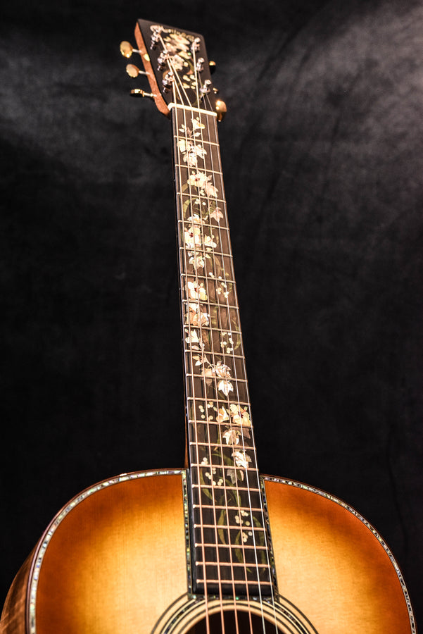 Acoustic guitar headstock with gold tuning pegs and bound fretboard