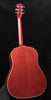 Red acoustic guitar with glossy finish, cream binding, and tuning keys