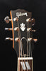 Gibson headstock with chrome tuning pegs and logo on dark backplate