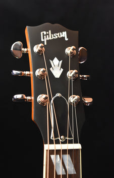 gibson headstock with chrome tuning pegs and logo on dark backplate