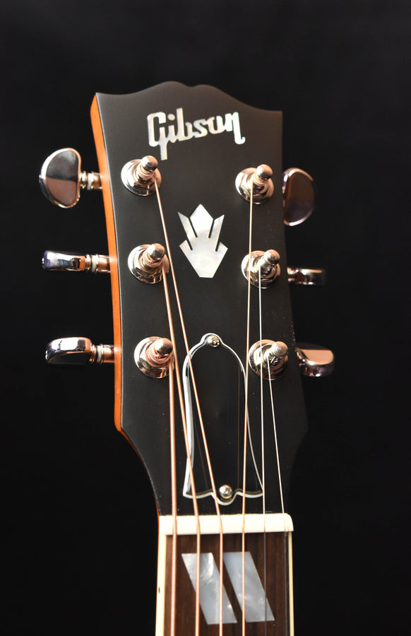 Gibson headstock with chrome tuning pegs and logo on dark backplate