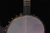 Open-back banjo neck and strings over gray drumhead with gold-toned rim hooks