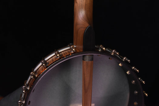angled view of open-back banjo rim and gray drumhead with walnut neck