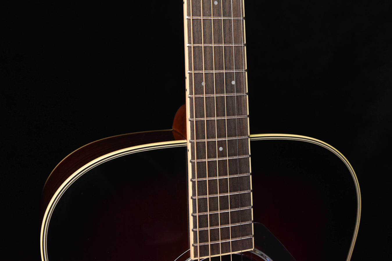 Acoustic guitar neck and fretboard, dot inlays and headstock edge visible
