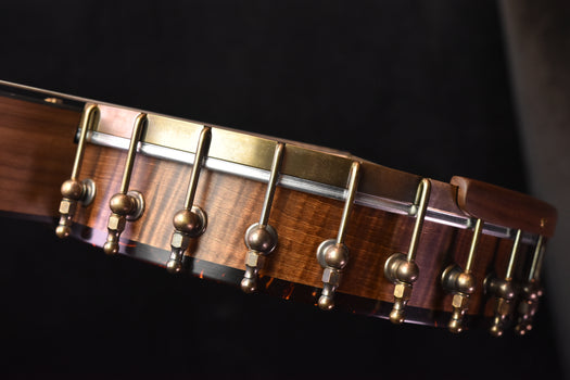 banjo tuning pegs and strings with chrome hardware along the walnut neck