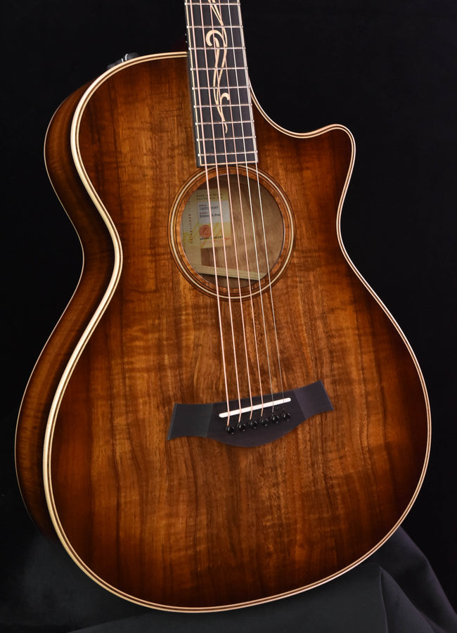 Taylor Koa acoustic guitar close-up of soundhole, strings, bridge, and glossy top finish