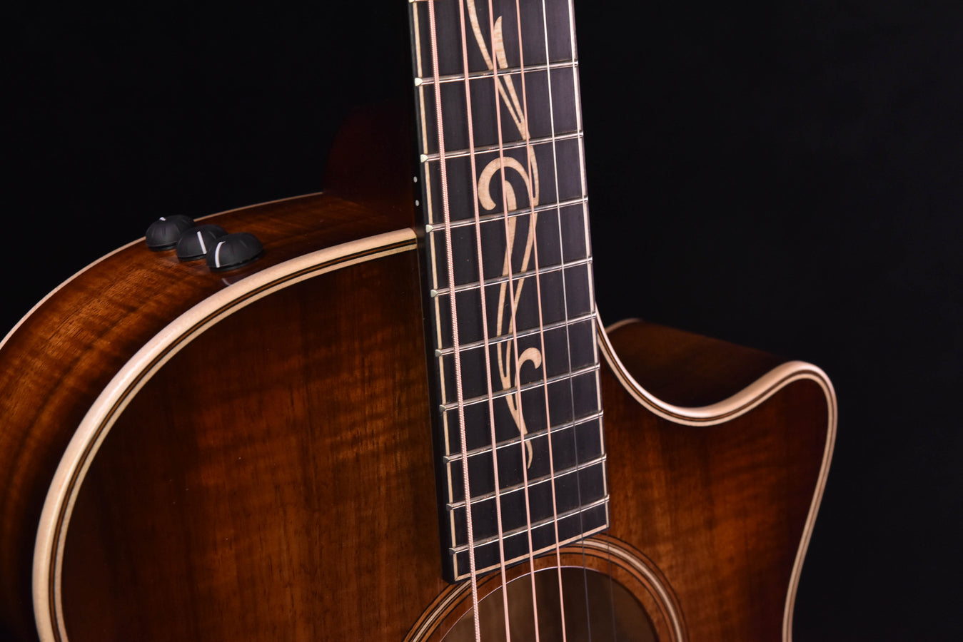 Koa acoustic guitar neck and headstock area with decorative inlays and tuning machines