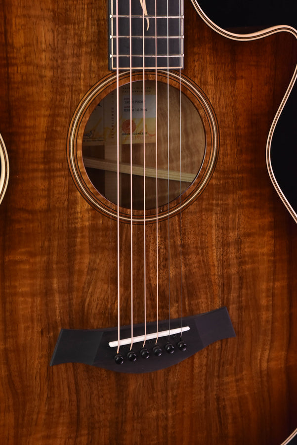 Koa acoustic guitar close-up of soundhole rosette, strings, and bridge hardware