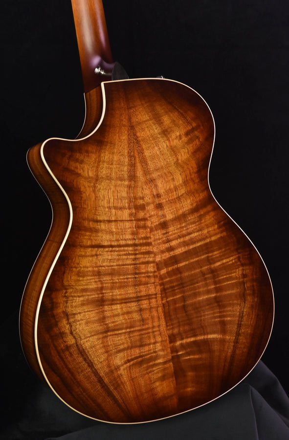 Koa acoustic guitar body close-up with visible figured wood grain and cream edge binding