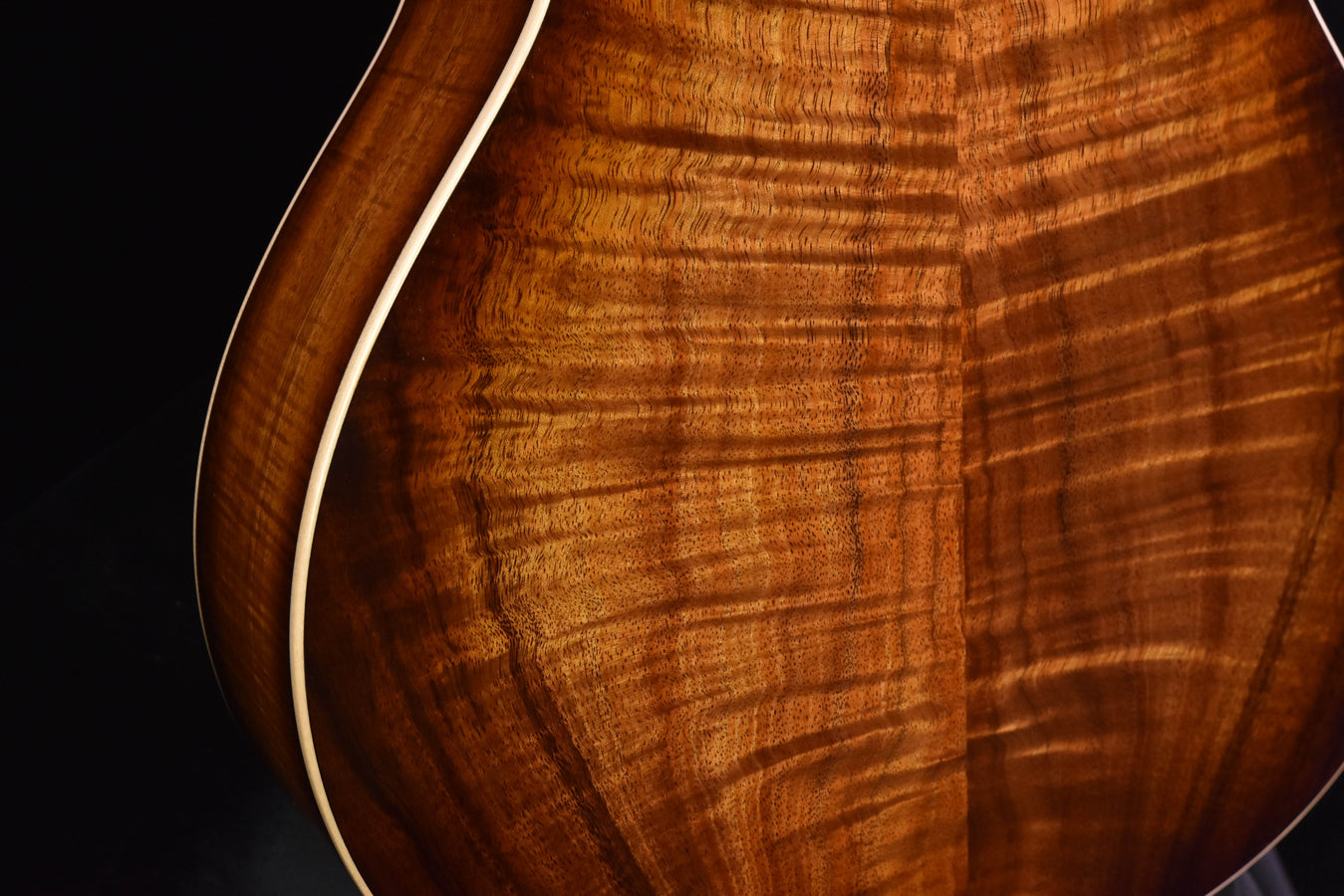 Koa guitar back close-up with detailed wood grain and curved binding