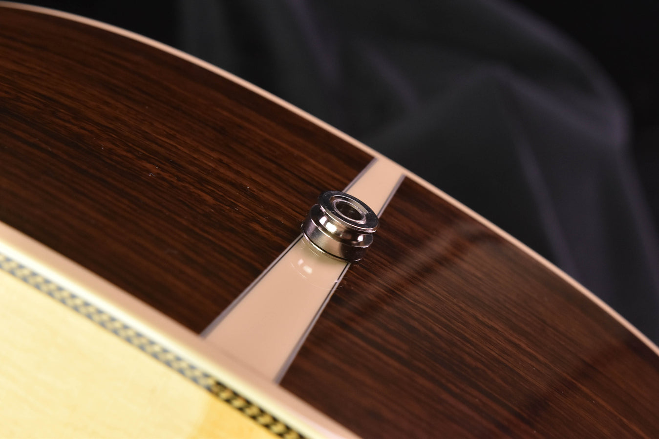 Metal strap button on the acoustic guitar body near the lower bout