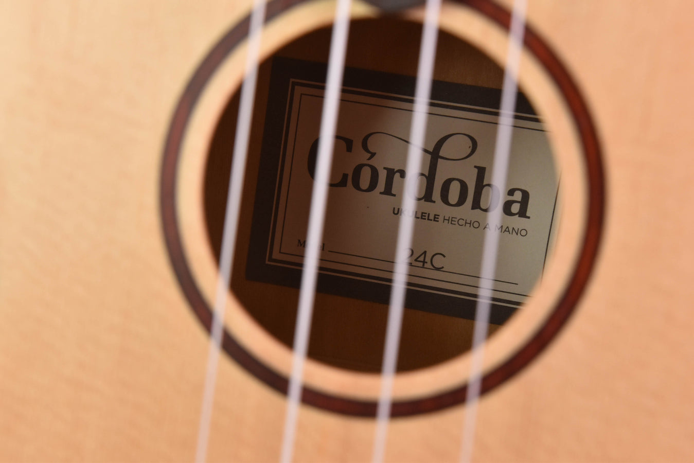 Ukulele-Schallloch mit sichtbarem runden Etikett und vier Saiten im Vordergrund
