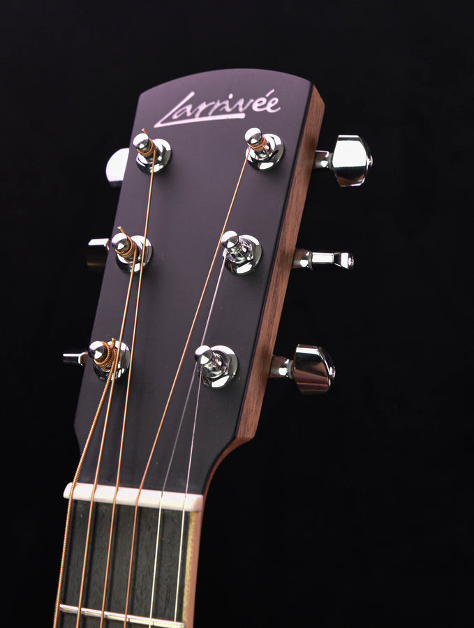 Guitar headstock close-up with tuning pegs and dark logo plate