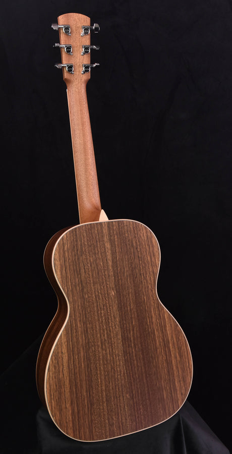 Acoustic parlor guitar back view with dark wood grain and metal tuning hardware at top