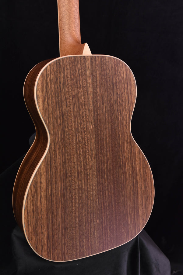 Guitar back view with warm brown wood grain and light binding around the body