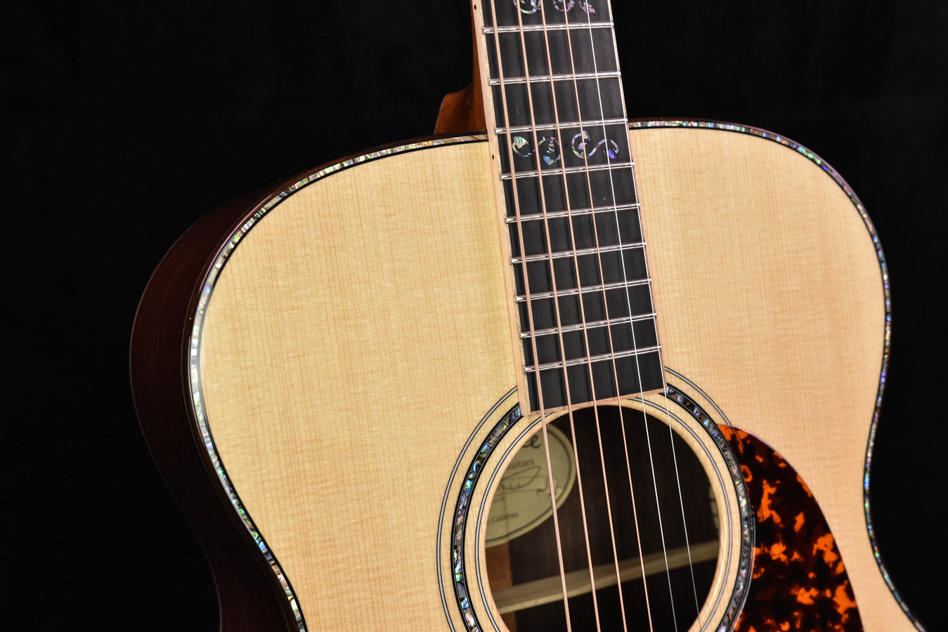 Close-up sound hole with tortoise pickguard, layered rosette and fretboard